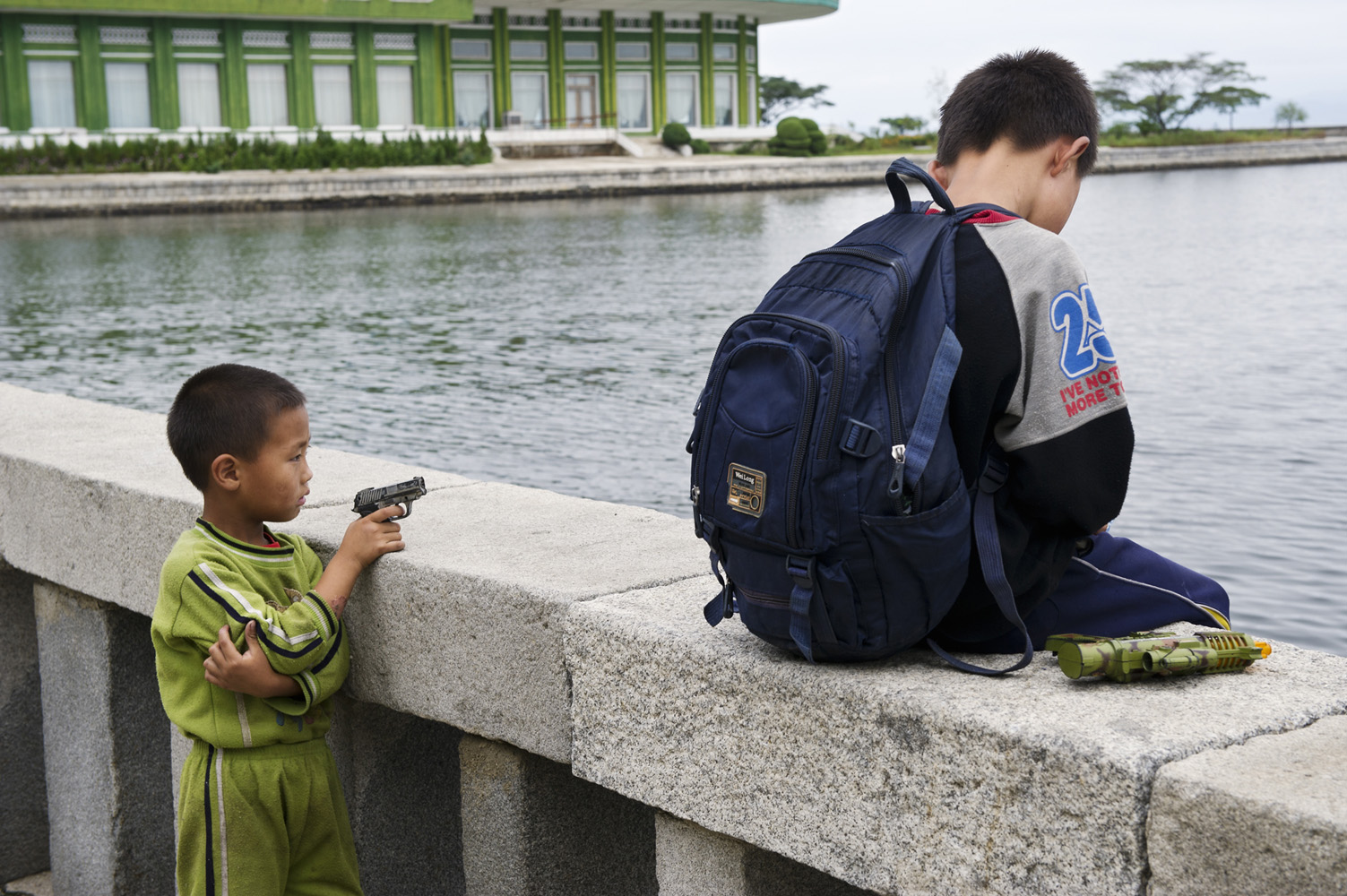 Kid playing with a toy gun in the harbour of WÅnsan, North Korea.